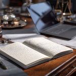 Notes sur les droits d'achat dans un carnet avec des papiers légaux et un ordinateur portable nearby.